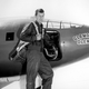 Yeager poses next to the X-1. The first X-1 was painted international orange to make it more visible. Later versions received white accents, and later aircraft were either bare aluminum or white. (NASA)
